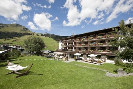 View of the side of Der Berghof Hotel and an Austrian Mountain with a hammock in foreground