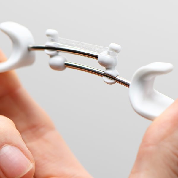 Close up of a Facial Flex device being compressed between finger and thumb