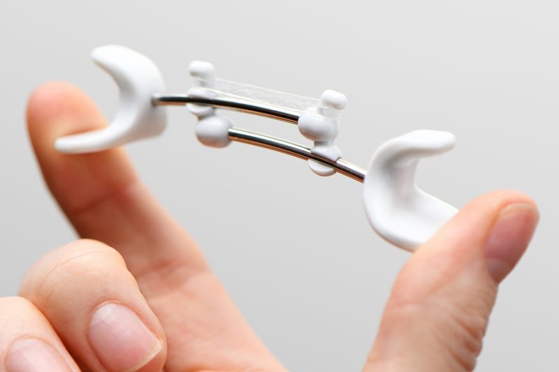 Close up of a Facial Flex device being compressed between finger and thumb