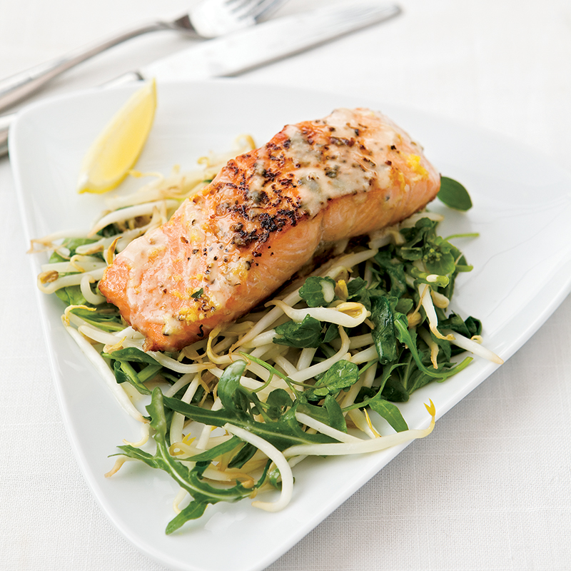A piece of baked salmon on a bed of stir fried beansprouts and green vegetables