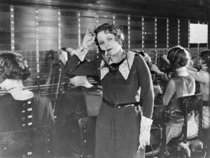 Use people's names on the telephone. Black and white photo of a weary telephone operator of the 1950's in a telephone exchange.