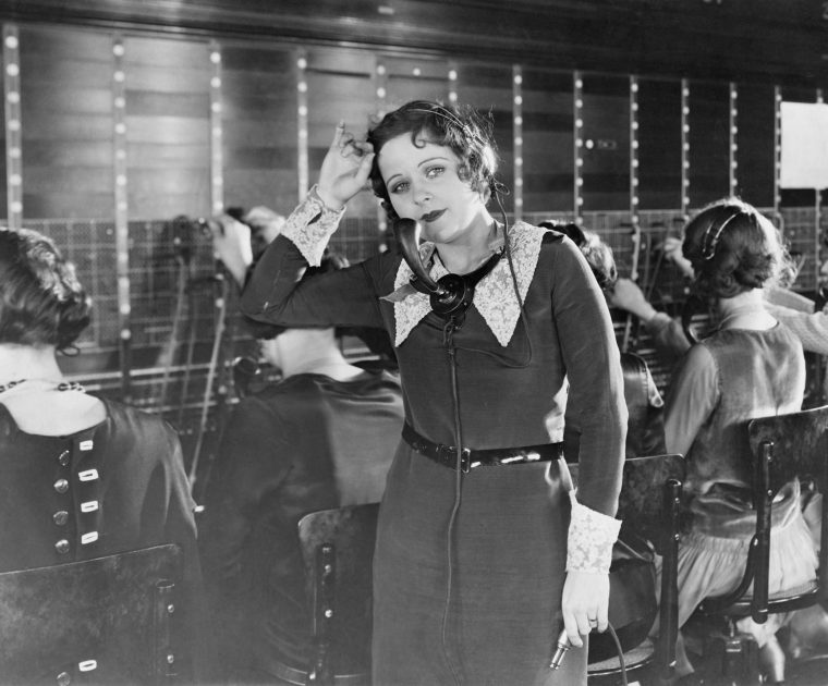 Use people's names on the telephone. Black and white photo of a weary telephone operator of the 1950's in a telephone exchange.