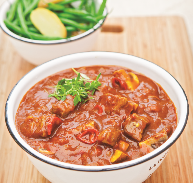 A bowl of Beef and Beer Stew with a side dish of green beans