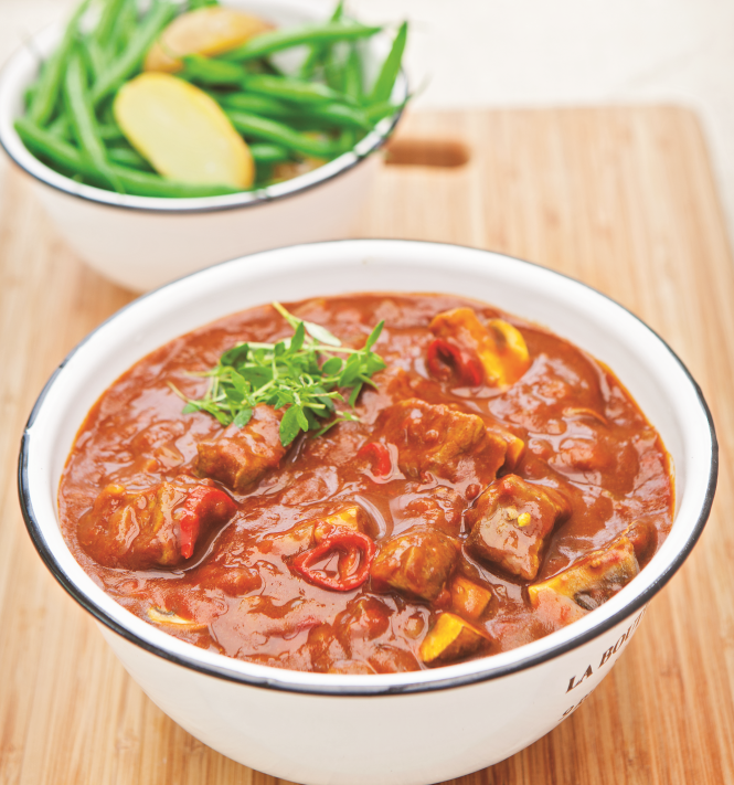A bowl of Beef and Beer Stew with a side dish of green beans