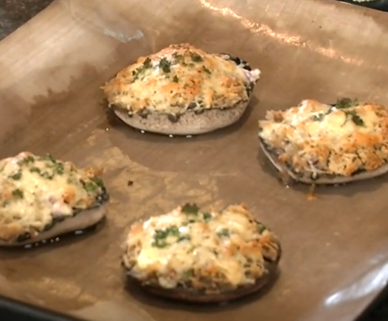Four grilled large flat mushrooms stuffed with cheese and breadcrumbs