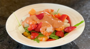 A bowl of Meditarranean Prawn Salad including prawns, strawberries, melon, tomatoes and salad leaves