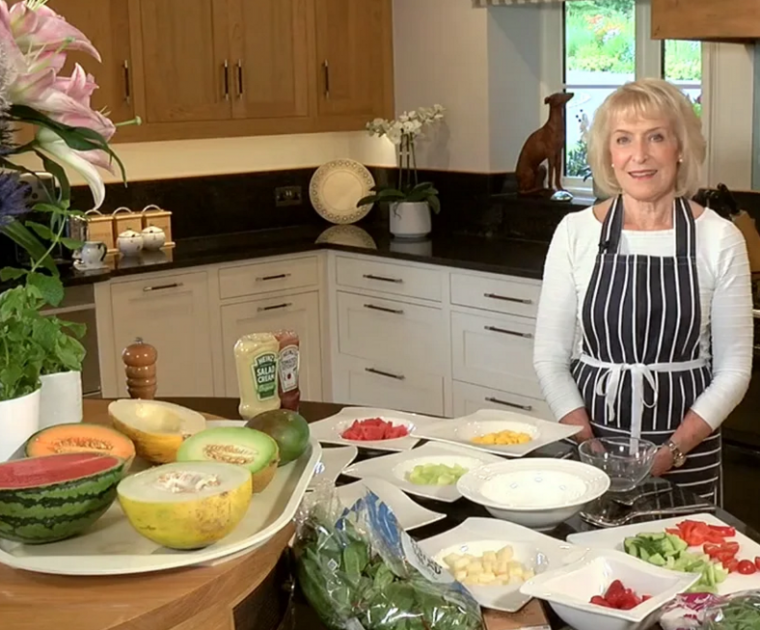 Rosemary Conley in her kitchen with an assortment of melons and other fruits and vegetables on the worktop