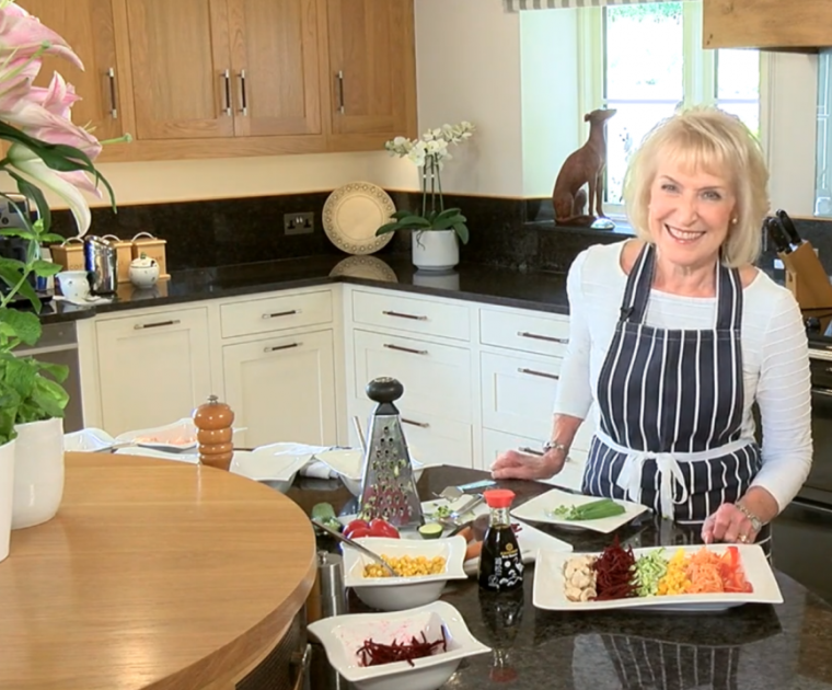 Rosemary Conley in her kitchen with various grated salad items on the worktop