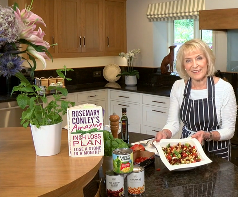 Rosemary Conley in her kitchen showing a bowl of mixed bean salad