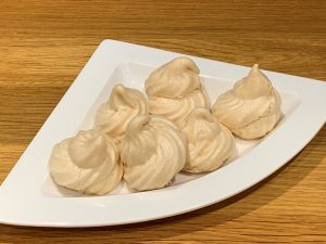 Aa white plate with a number of piped meringues.