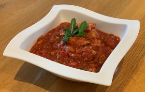 Chicken Jalfrezi in a white square dish garnished with a sprig of mint
