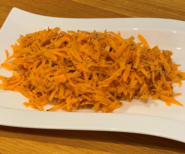 A salad of raw grated sweet potato on a rectangular white plate
