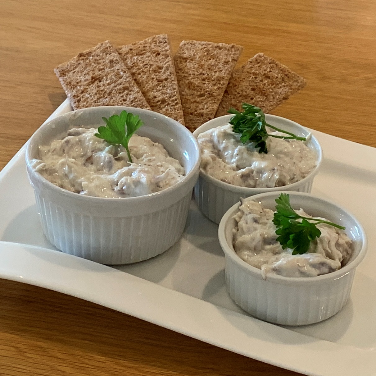Mackerel Pate in small round ramekin bowls with crispbreads and garnished with parsley