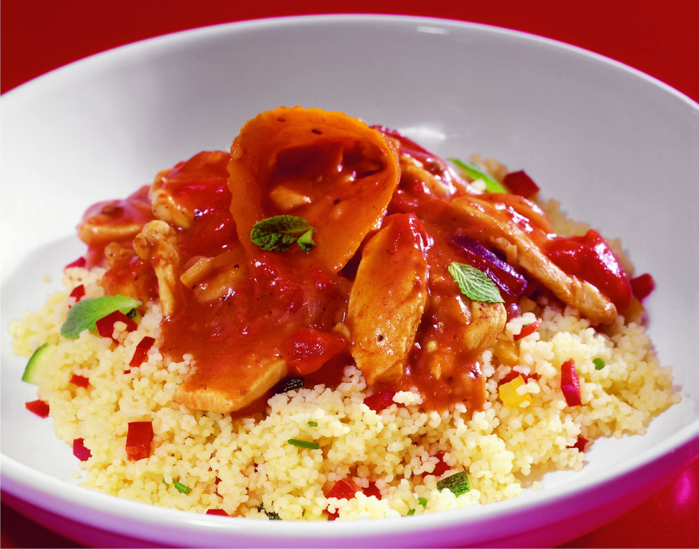Tunisian Chicken in a rich, spicy orange sauce served on a bed of couscous