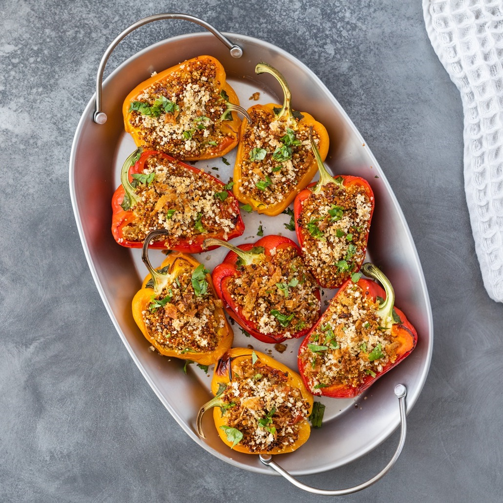 Halved bell peppers stuffed with tomatoes, garlic and sardines, baked in a white oven-proof dish