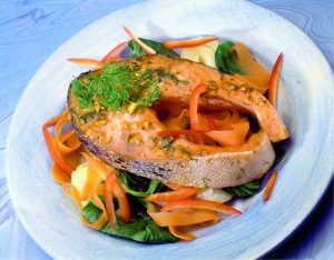 Baked salmon with ginger. A glazed baked salmon steak complete with skin on a bed of salad leaves sprinkled with ginger and dill