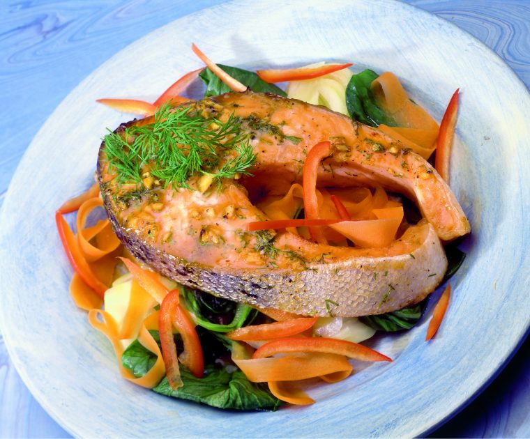 Baked salmon with ginger. A glazed baked salmon steak complete with skin on a bed of salad leaves sprinkled with ginger and dill