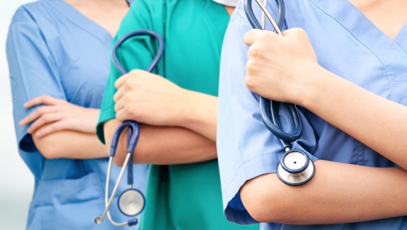 Three medical staff dressed in scrubs. Two carry sthoscopes