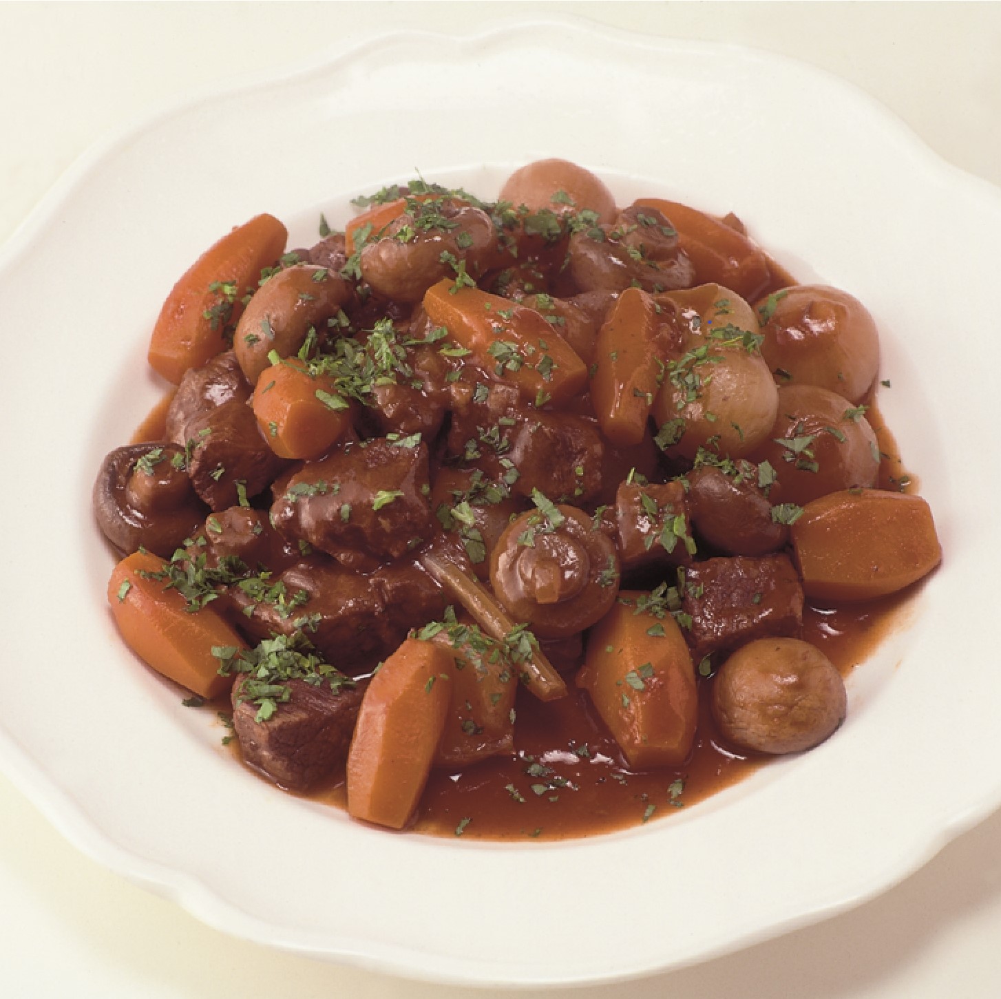 Plate of Beef Bouguignon with beef, carrots, mushrooms and celery in a tomato based gravy sprinkled with fresh thyme