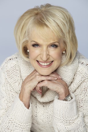 Rosemary Conley head and shoulders wearing a thick knitted white jumper with chin resting on her clasped hands