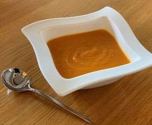 Sweet Potato and Ginger Soup in a square white bowl with a spoon
