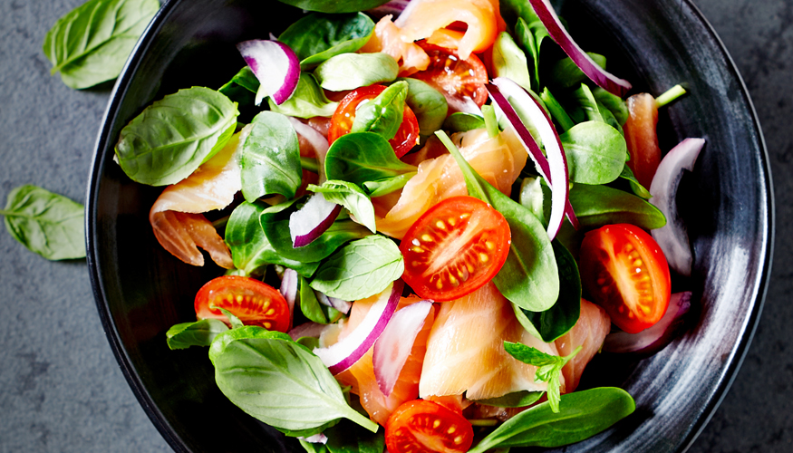 Good nutrition - A mix of fresh salad leaves, tomatoes and onions in a round grey bowl
