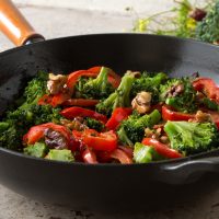 A frying pan with broccoli and red pepper stir fry