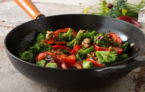 A frying pan with broccoli and red pepper stir fry