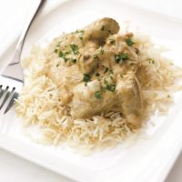Chicken Korma on a bed of white rice is chunks of tender chicken in a creamy looking sauce sprinkled with finely chopped corriander.