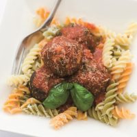 Quorn Leek & Sage Meatballs on a bed of Fusilli pasta sprinkled with grated cheese and garnished with fresh basil leaves