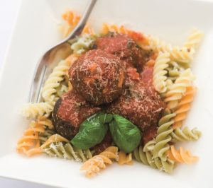 Quorn Leek & Sage Meatballs on a bed of Fusilli pasta sprinkled with grated cheese and garnished with fresh basil leaves