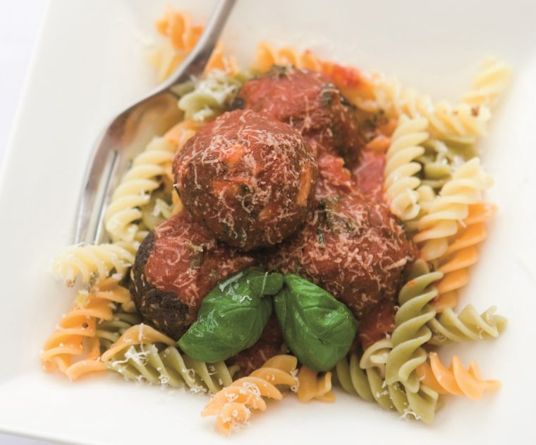 Quorn Leek & Sage Meatballs on a bed of Fusilli pasta sprinkled with grated cheese and garnished with fresh basil leaves
