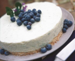Lime cheesecake is a beautiful round dessert with a creamy looking cheesecake topping ona thin crumbly biscuit base, garnished with fresh blueberries